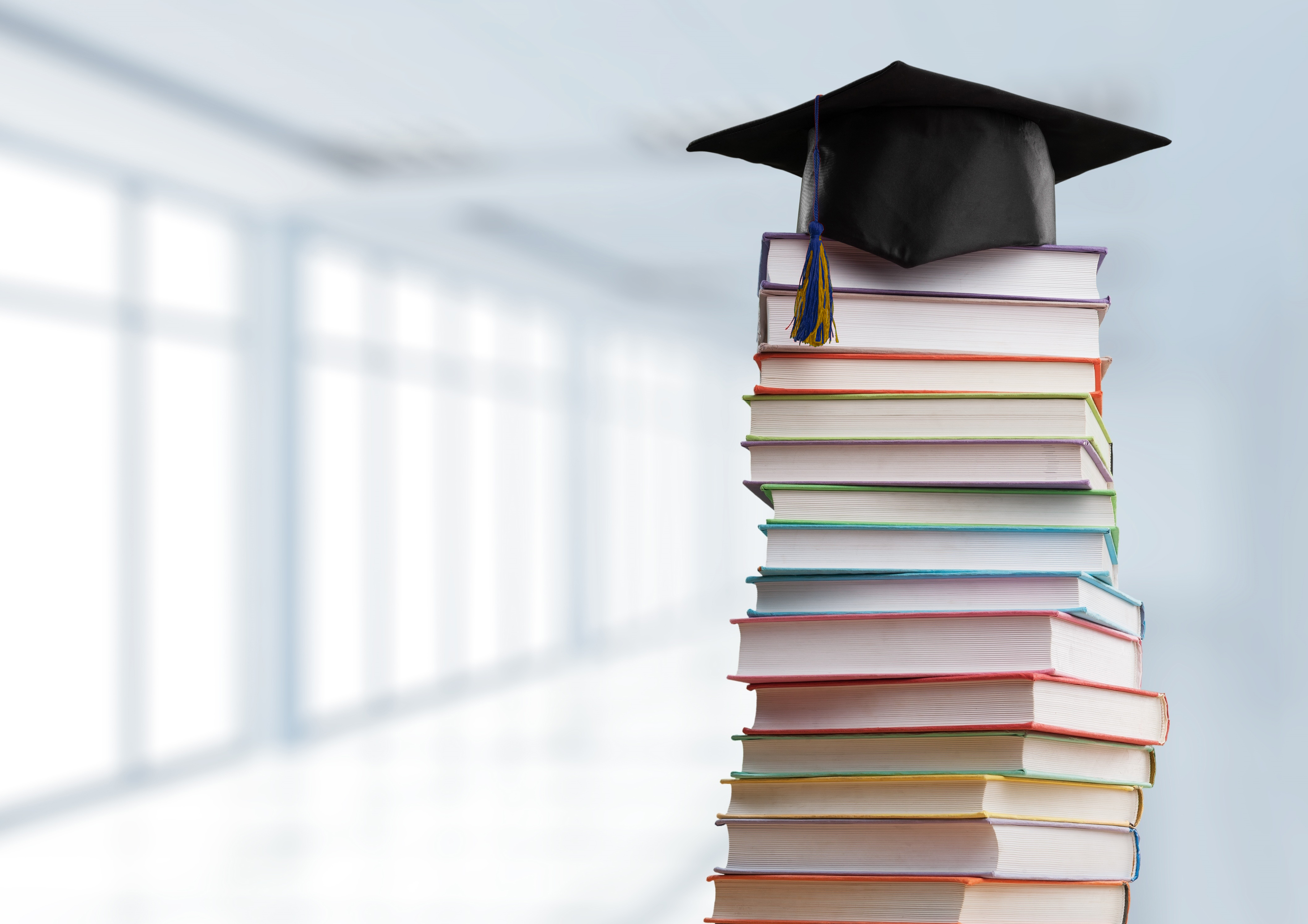 Stack of books with graduation cap on top