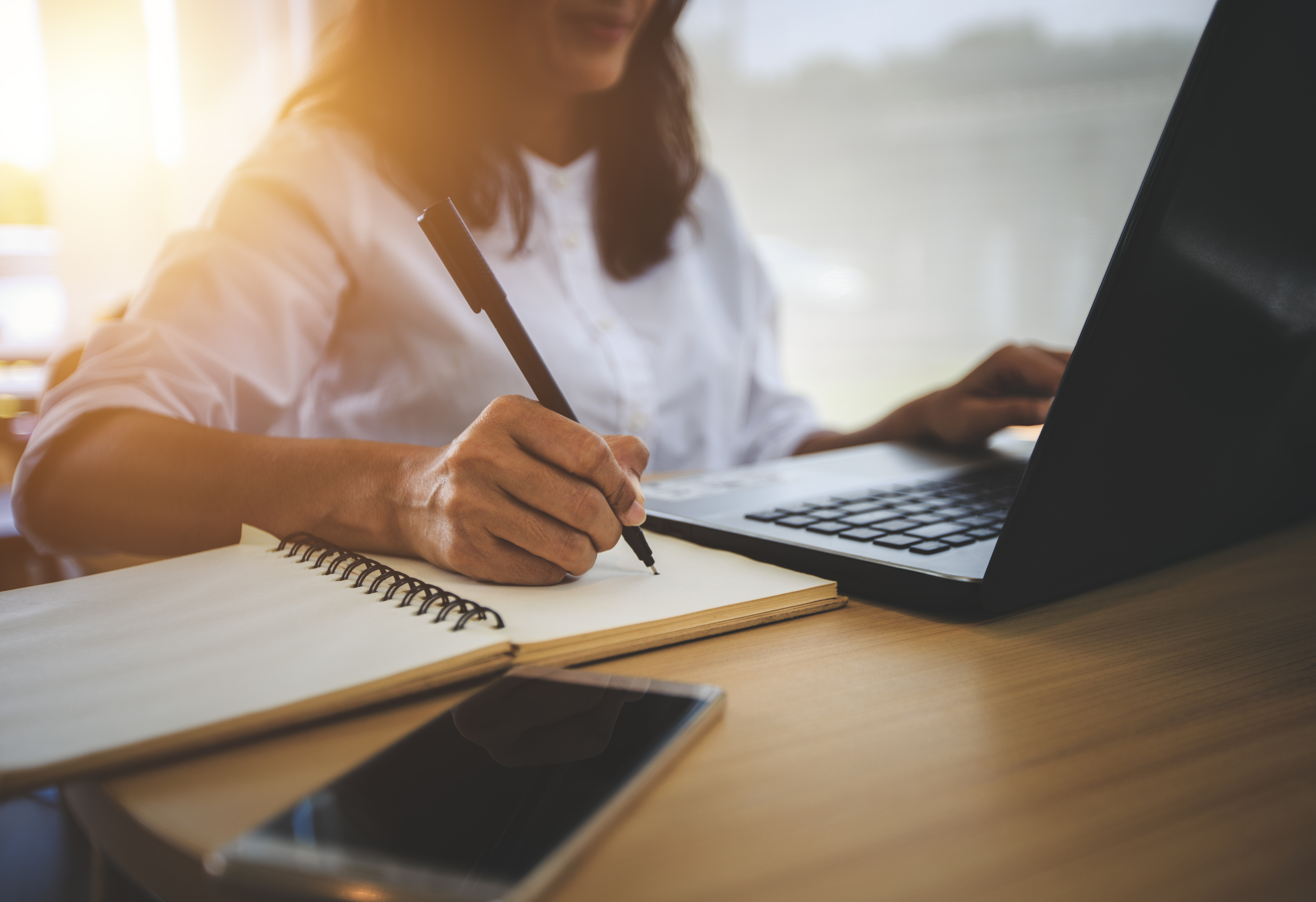 Women writing and working on laptop