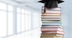 Stack of books with graduation cap on top